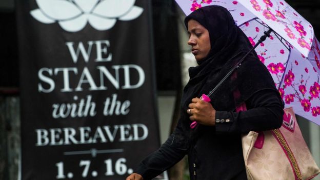 A Bangladeshi woman walks past a banner that reads 