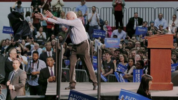 Bernie Sanders throws his suit coat to the crowd at a campaign rally in a hot gymnasium in Milton, Massachusetts, on Monday