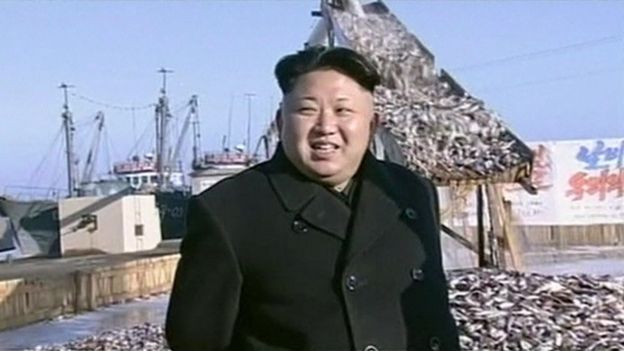 Kim Jong-Un in front of a chute down which fish are pouring, in a harbour in North Korea
