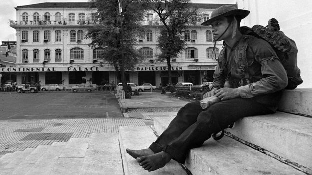 a soldier of the National Liberation Forces (NLF) of North Vietnam surveying the National Assembly building in Saigon