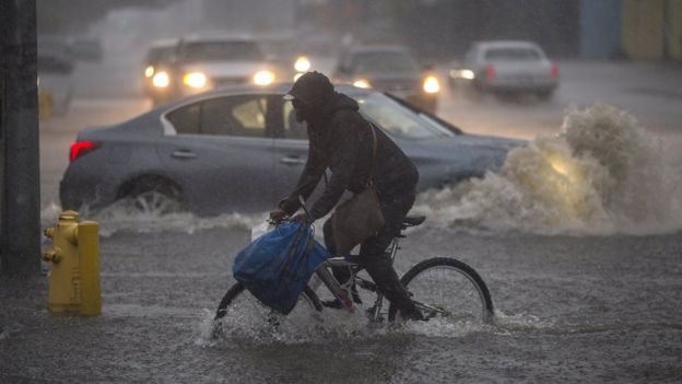 A man tries to cycle through the flooded streets of Sun Valley, southern California