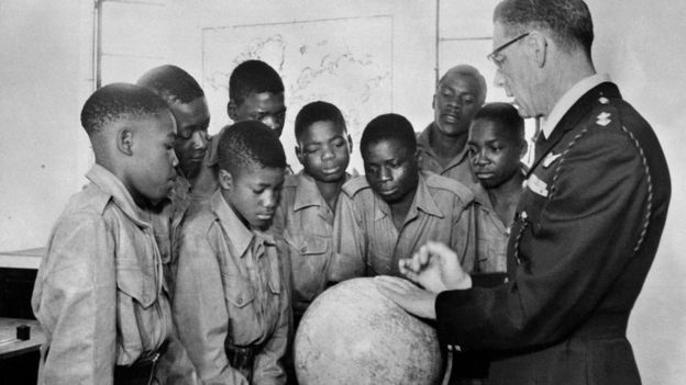 A colonial officer teaches geography to a group of school kids in Rhodesia