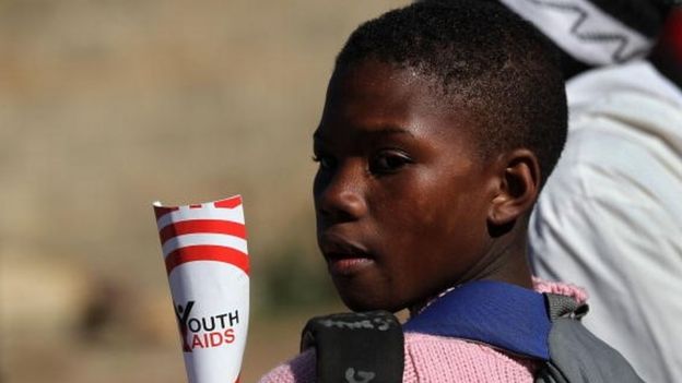 A Soweto youth holds HIV/AIDS awareness literature while watching a street soccer match held by the non-profit Population Services International (PSI), ahead of a World Cup game on June 16, 2010 in Soweto, Johannesburg