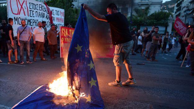 An anti-EU protester burns an EU flag in front of the European Commission offices in Athens on July 2, 2015, during a demonstration supporting the no vote for the upcoming referendum