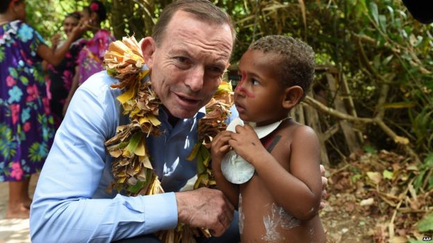 Australian Prime Minister Tony Abbott speaks with a child after laying a wreath on Eddie Mabo's grave on Mer Island in the Torres Strait