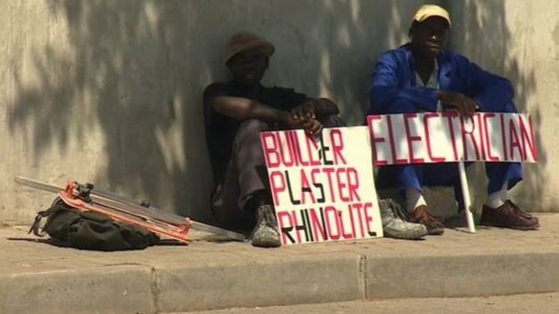 Men in South African touting for work holding the signs
