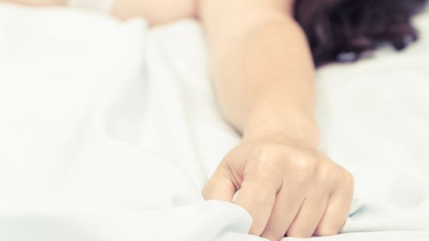 Mano de una mujer sujetando una sábana durante un orgasmo