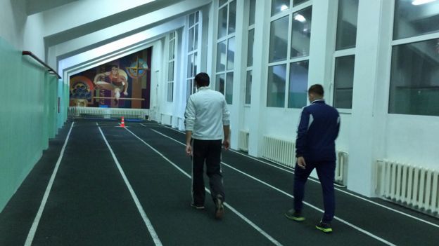 Two men walk on an indoor track in Kursk