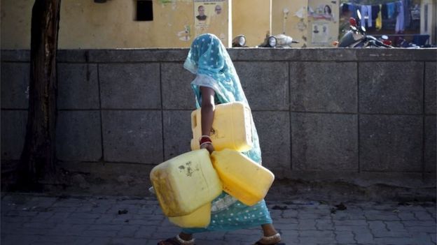 A woman carries empty containers to fetch water from a municipal water tap in New Delhi, India, February 21, 2016.