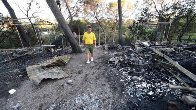 A man looks at the damage at a campsite following a wildfire in Bagnols-en-Foret