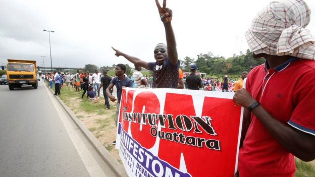 Members and supporters of the Ivorian Popular Front (FPI) party hold a banner as they protest against President Alassane Ouattara's new constitution, in Abidjan on 8 October