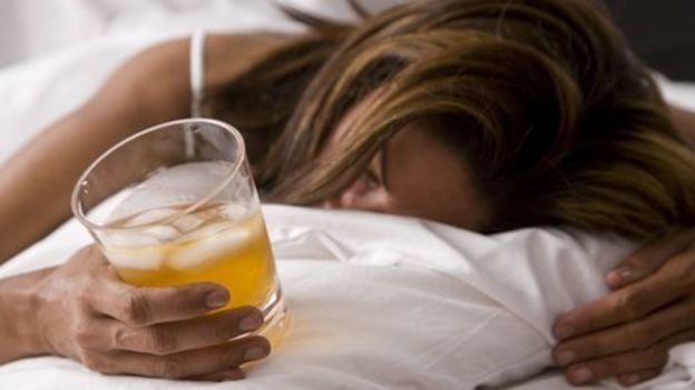 Woman in bed holding drink