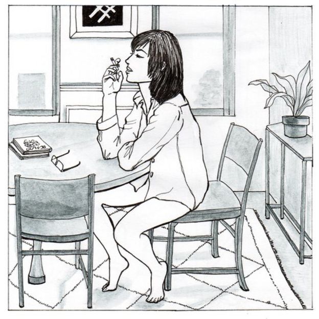 Mujer fumando en la cocina en camisa.