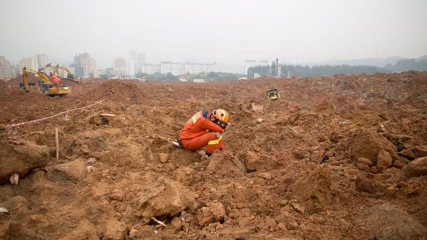 An exhausted rescuer takes a rest as he sits on the mud left behind by the Shenzhen landslide
