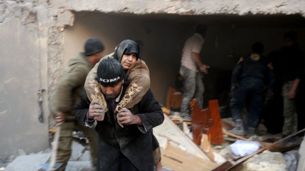 A man carries a woman rescued from a building damaged a reported government air strike in the rebel-held Hamra district of Aleppo (20 November 2016)