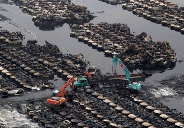 This picture taken on 20 August 2015 shows rescuers cleaning up damaged cars during the explosions in Tianjin