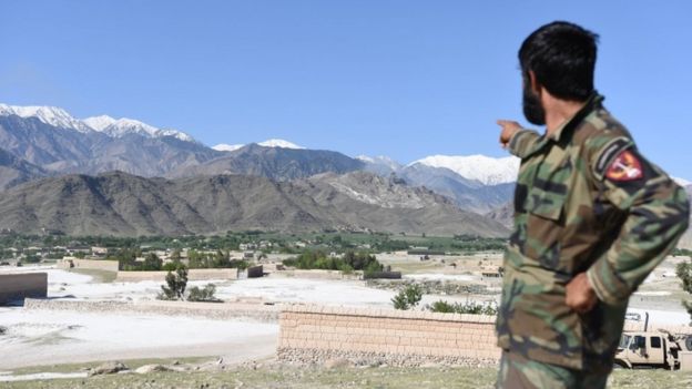 An Afghan soldier points to the area where the US dropped the bomb