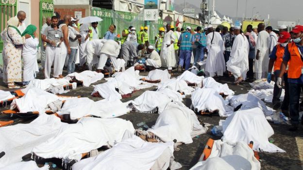 Saudi emergency personnel stand near bodies of Hajj pilgrims at the site where at least 717 were killed and hundreds wounded in a stampede in Mina