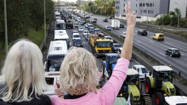 People standing on a bridge wave as French farmers converge on Paris (03 September 2015)