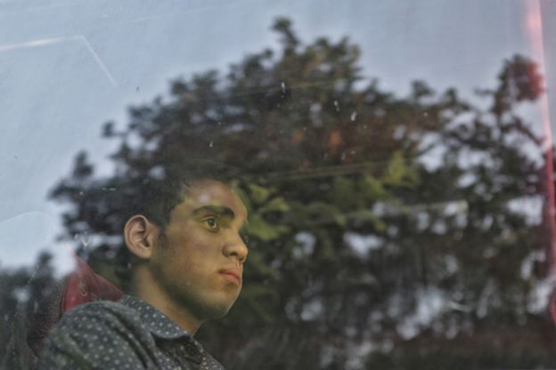Young man stares out of bus window