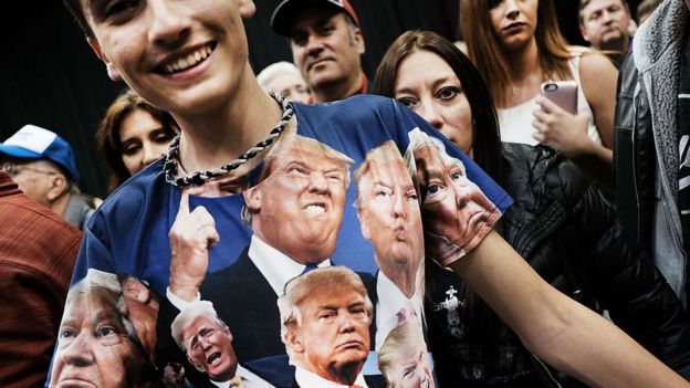 Un adolescente posa para la cámara con una camiseta con varias caras de Trump.