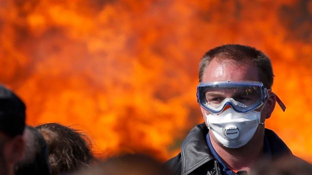 A striking French labour union employee stands near a burning barricade at a fuel depot near the Donges oil refinery