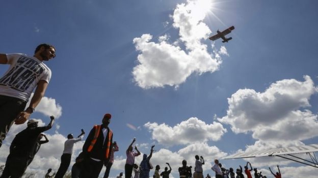 A vintage biplane flies over spectators during the Vintage Air Rally held at Nairobi National Park, in Nairobi (27 November 2016)