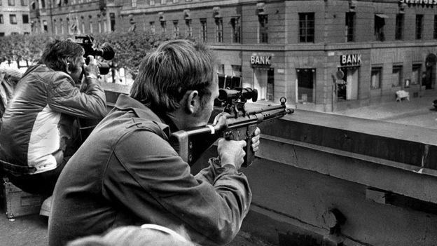 Policía armado y periodista con cámara