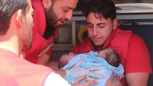 Red Crescent workers hold the babies