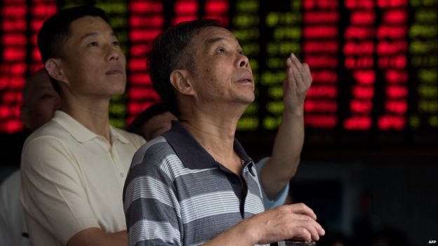 Investors monitor screens showing stock market movements at a brokerage house in Shanghai on 13 August 2015.