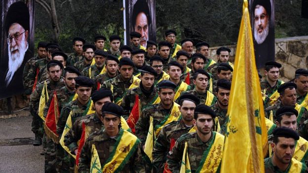 Combatientes de Hezbollah marchan frente a las imágenes de líderes de Irán y Hezbollah