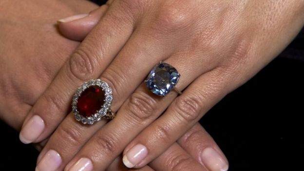 A model with a pigeon's blood ruby ring (L) and the cushion-shaped blue diamond ring at Sotheby's in Geneva (11 November 2015)