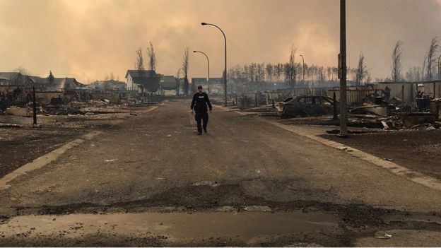 A Mountie surveys the damage on a street in Fort McMurray, 5 May 2016