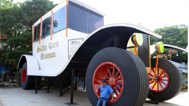 Indian car designer Sudhakar Yadav poses next to a large stationary car - modelled on the 1922 Ford Tourer - at the Sudha Cars Museum in Hyderabad