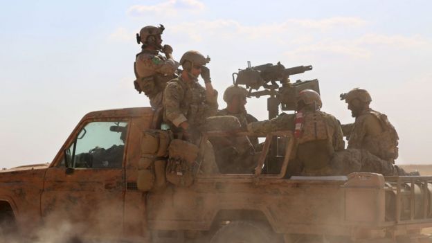 Armed men in uniform identified by Syrian Democratic forces as US special operations ride in the back of a pickup truck in the northern Syrian province of Raqqa on May 25, 2016.