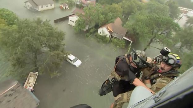 Two rescuers from US Navy Helicopter Sea Combat Squadron 7 are lowered to a house after Tropical Storm Harvey flooded a neighbourhood in Beaumont, Texas, 30 August