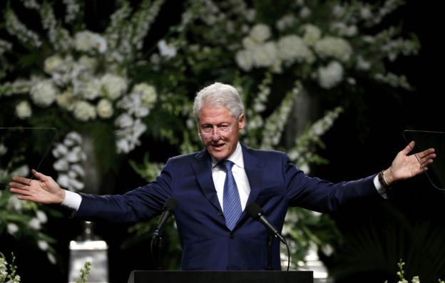 Bill CLinton on stage at Ali memorial service, with arms stretched wide