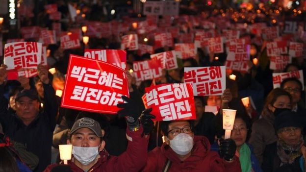 Protesters in Seoul hold banners that read: 