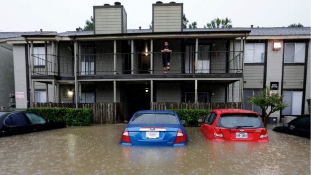 A resident looks out f-rom the second floor as floodwaters surround his apartment complex Monday, April 18, 2016, in Houston