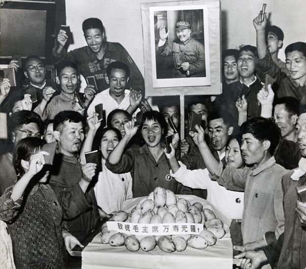 People celebrate around a plate of mangoes