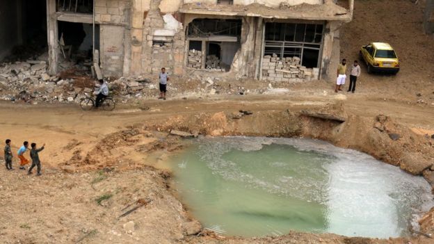 Residents of rebel-held Tariq al-Bab district inspect water-filled crater that activists say was caused by bunker-busting bomb (23 September 2016)