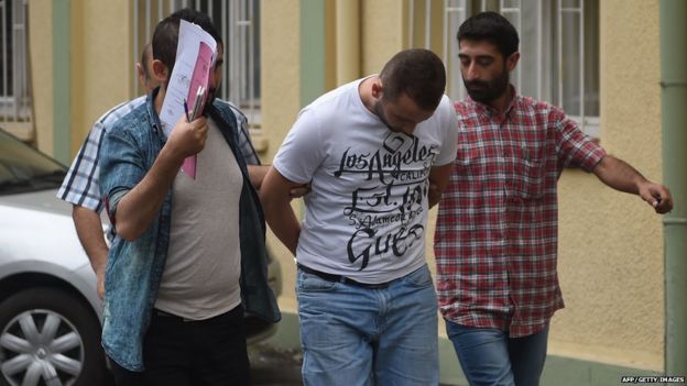 Turkish plainclothes police officers escort a suspected member of the Islamic State (IS) group at a hospital for a medical check-up on 24 July 2015 in Istanbul.
