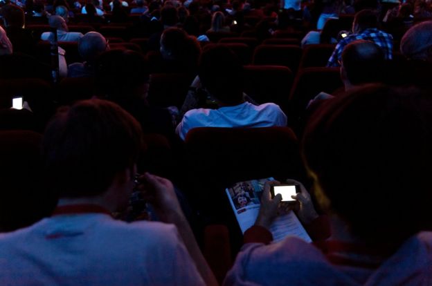 People use their phones in a cinema auditorium