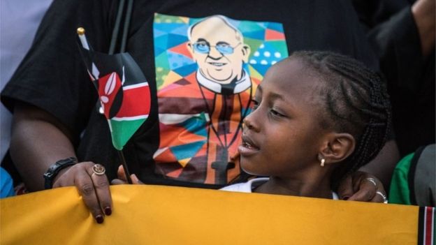 A young girl waits on the roadside for Pope Francis' convoy to drive through the capital from the airport on 25 November 2015 in Nairobi, Kenya