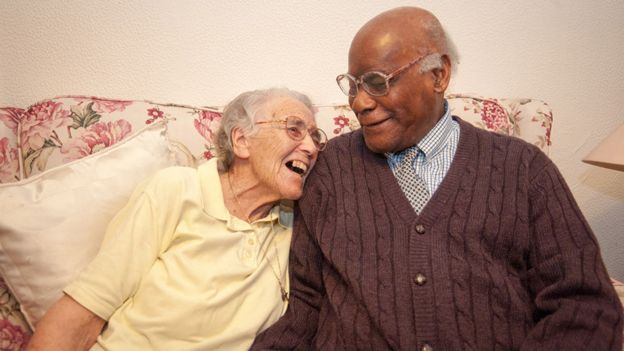 Trudy and Barclay Patoir laugh, sitting on the sofa