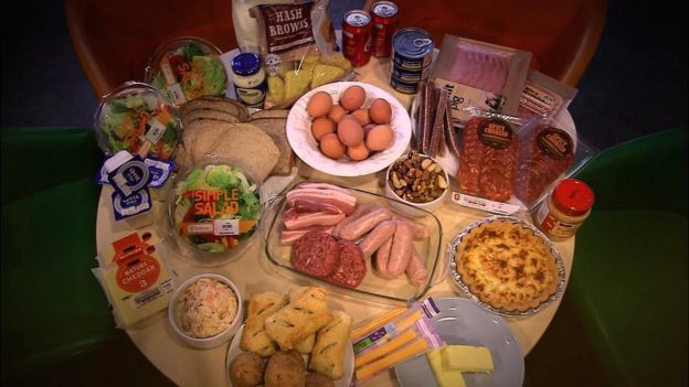 A table of food including sausages, burgers, quiche, eggs, cheese, yoghurt, chorizo, mayonnaise, hash browns and peanut butter