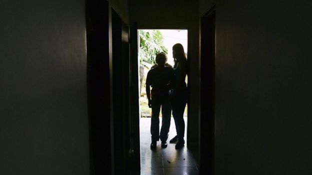 Anciando con Alzheimer siendo guiado por otras dos personas.