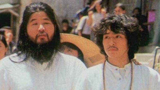 Shoko Asahara of Aum Shinri Kyo, left, walks in Tokyo accompanied by his top disciple Yoshihiro Inoue, right, in an undated photo