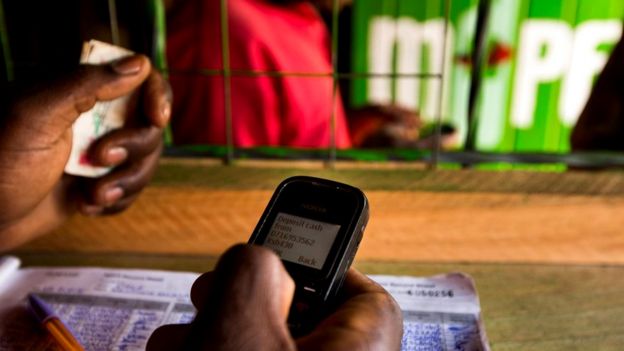Работник магазина, использующего систему M-Pesa, в столице Кении Найроби, где миллионы операций теперь осуществляют при помощи мобильных телефонов