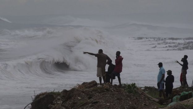 People stand on the coast watching the surf produced by Hurricane Matthew, on the outskirts of Kingston, Jamaica